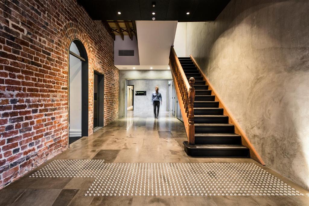 a person walking down a staircase in a brick building at Hougoumont Hotel Fremantle in Fremantle