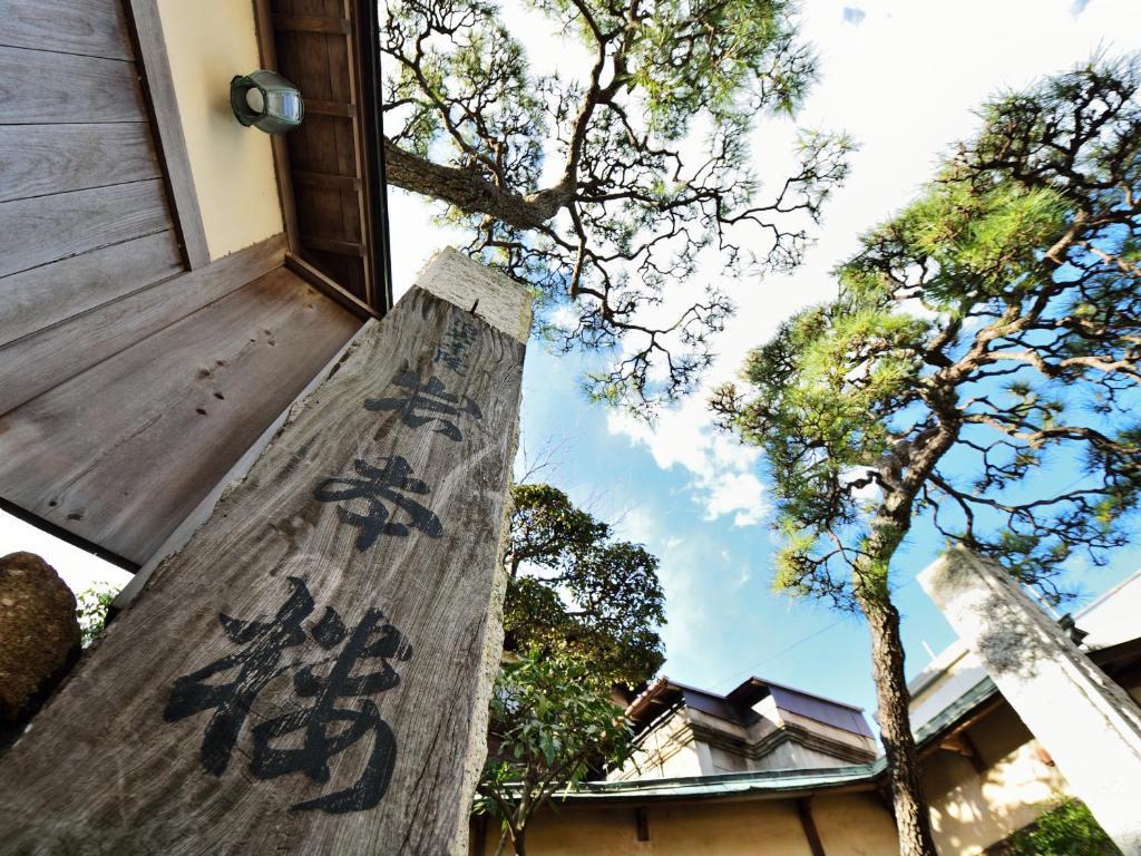 a wooden pole with writing on it next to trees at Iwamotoro in Fujisawa