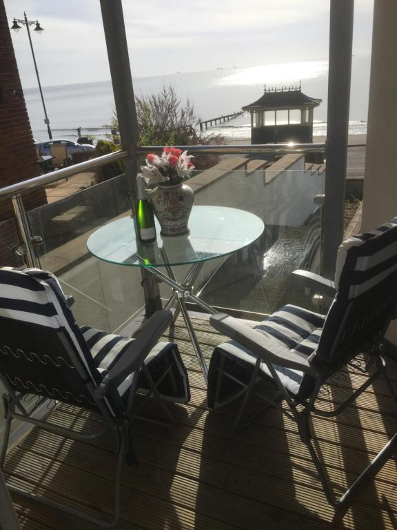 a table and chairs on a balcony with a view of the ocean at Tides Reach in Shanklin