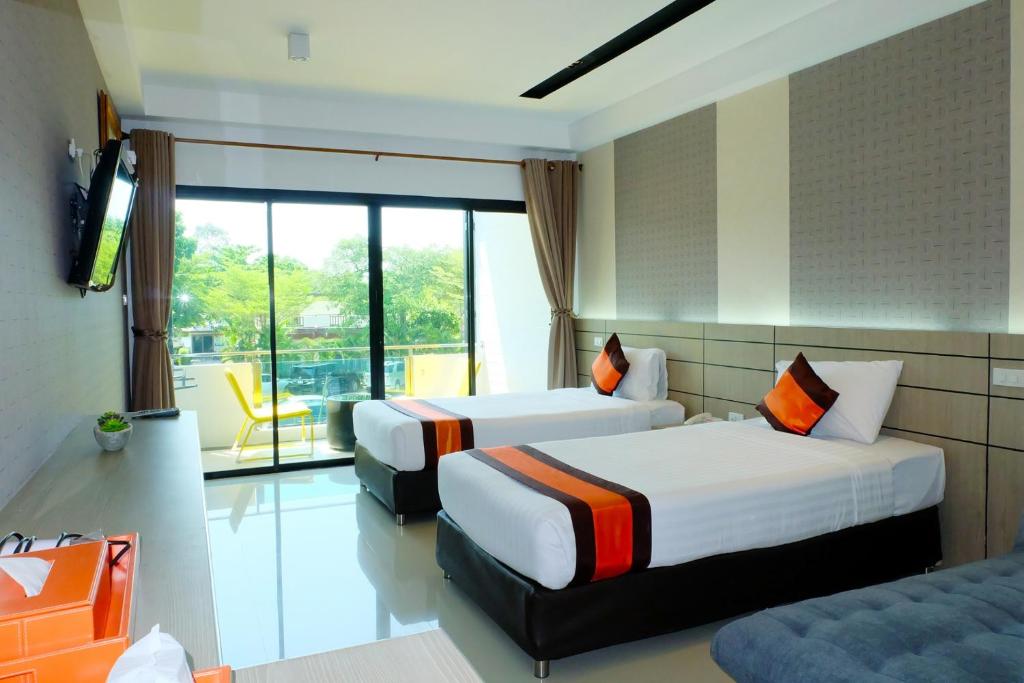 a hotel room with two beds and a television at Chaolao Cabana Resort in Chao Lao Beach