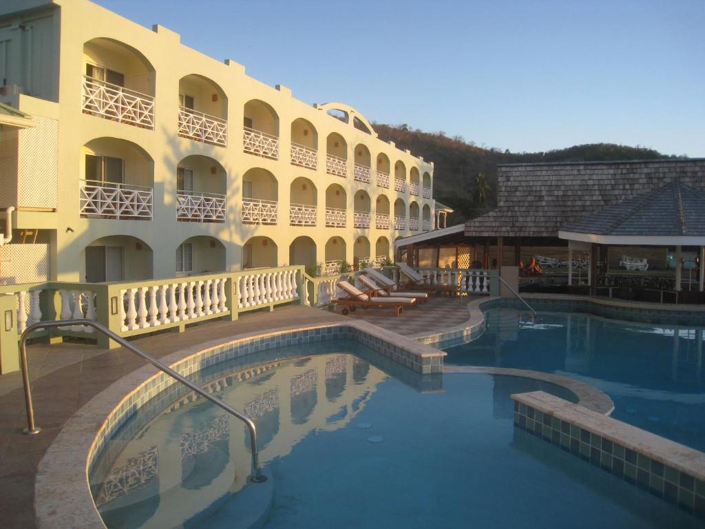 a hotel with a swimming pool in front of a building at Kalinago Beach Resort in Saint Georgeʼs