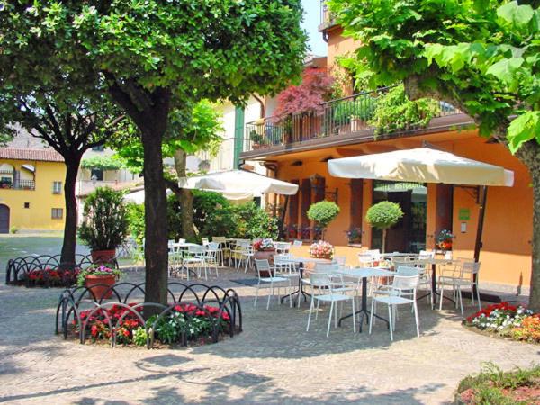 a patio with tables and chairs and umbrellas at Hotel Don Abbondio in Lecco