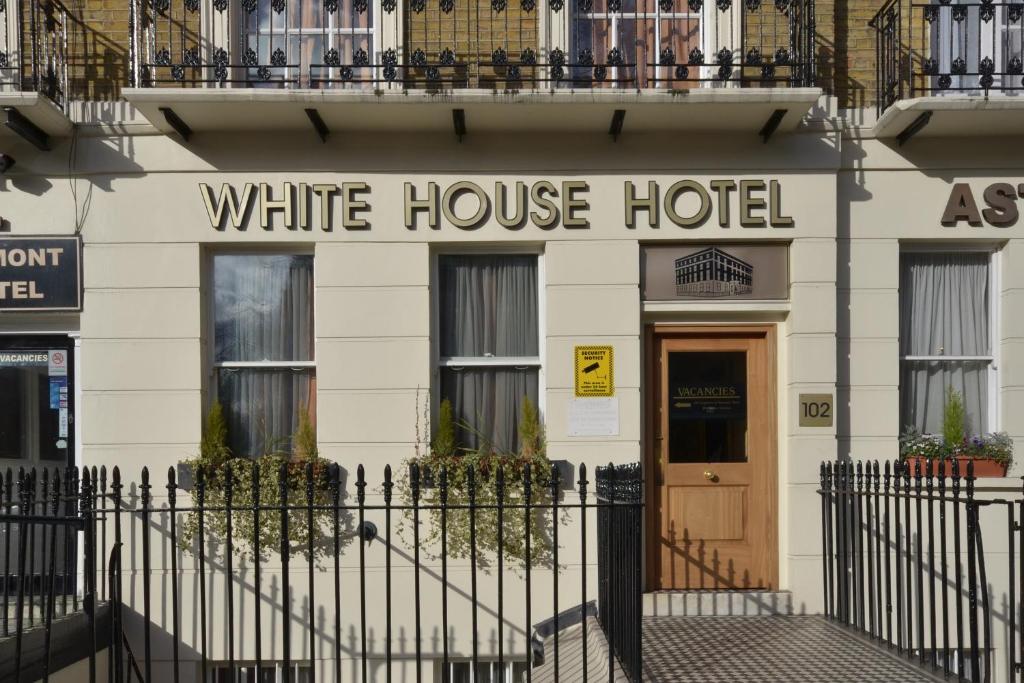 ロンドンにあるホワイト ハウス ホテルの白い家のホテルで、目の前に黒い柵があります。