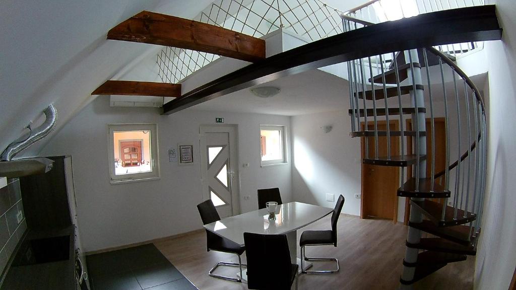 a dining room with a table and a spiral staircase at Apartma Jernej in Bovec