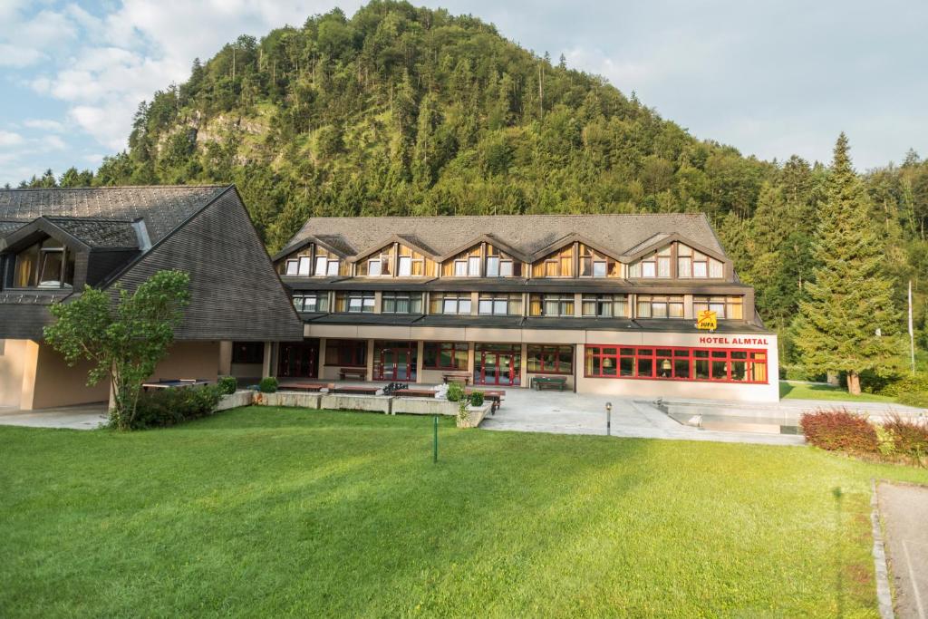 uma casa grande com um grande relvado em frente a uma montanha em JUFA Hotel Grünau im Almtal em Grünau im Almtal