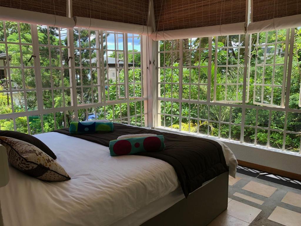 een slaapkamer met een bed en een groot raam bij Villa Sirandane in Baie du Tombeau
