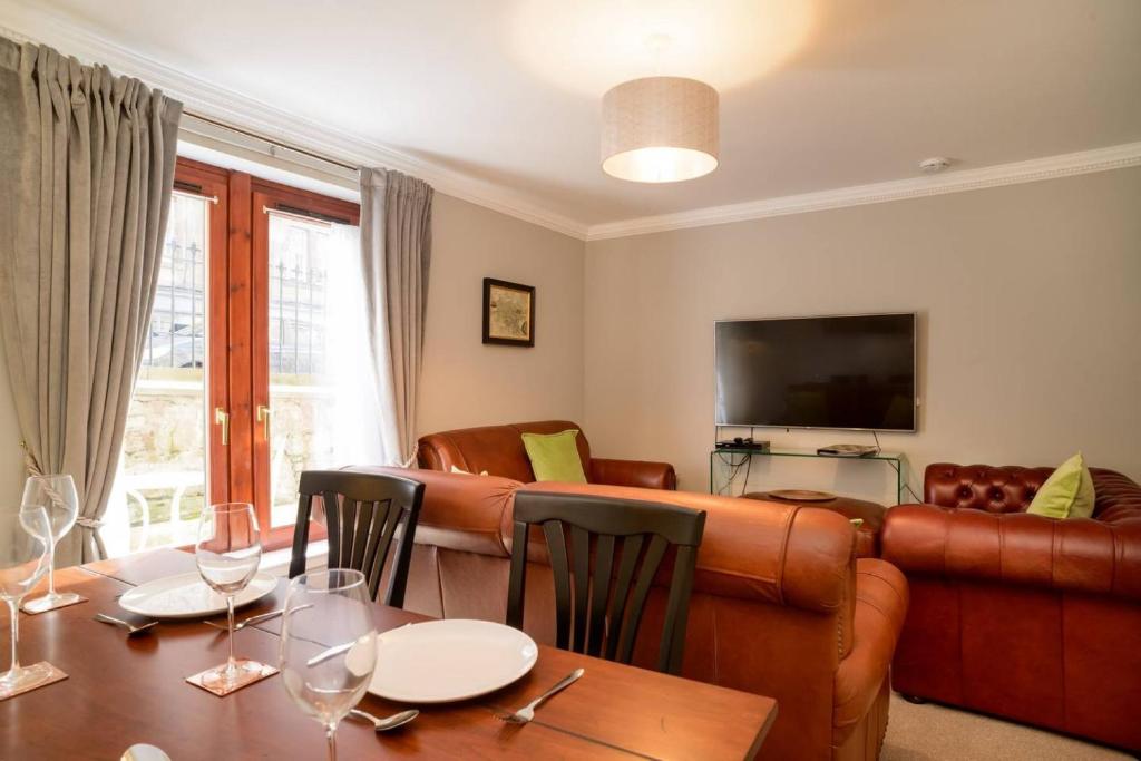 ALTIDO Elegant 2 bed, 2 bath flat, patio and free parking في إدنبرة: غرفة معيشة مع طاولة وأريكة