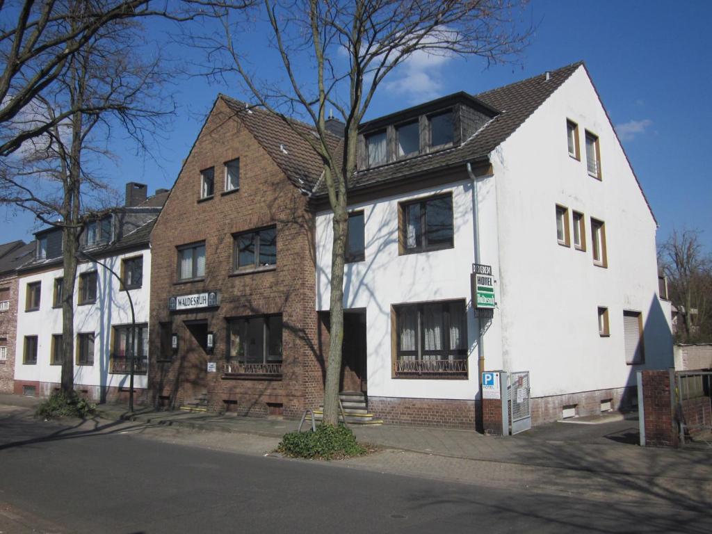 ein weißes und braunes Gebäude an der Ecke einer Straße in der Unterkunft Hotel Waldesruh in Düsseldorf