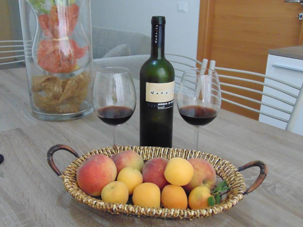 a basket of fruit and a bottle of wine on a table at casa francesca in Castellammare del Golfo