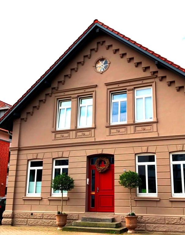 een huis met een rode deur en een klok bij Ferienwohnung Schönwälder in Buxtehude