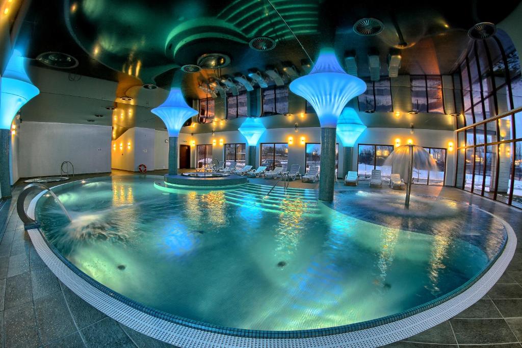ein großes Schwimmbecken in einem Gebäude mit blauen Lichtern in der Unterkunft Hotel Arkas in Proskau