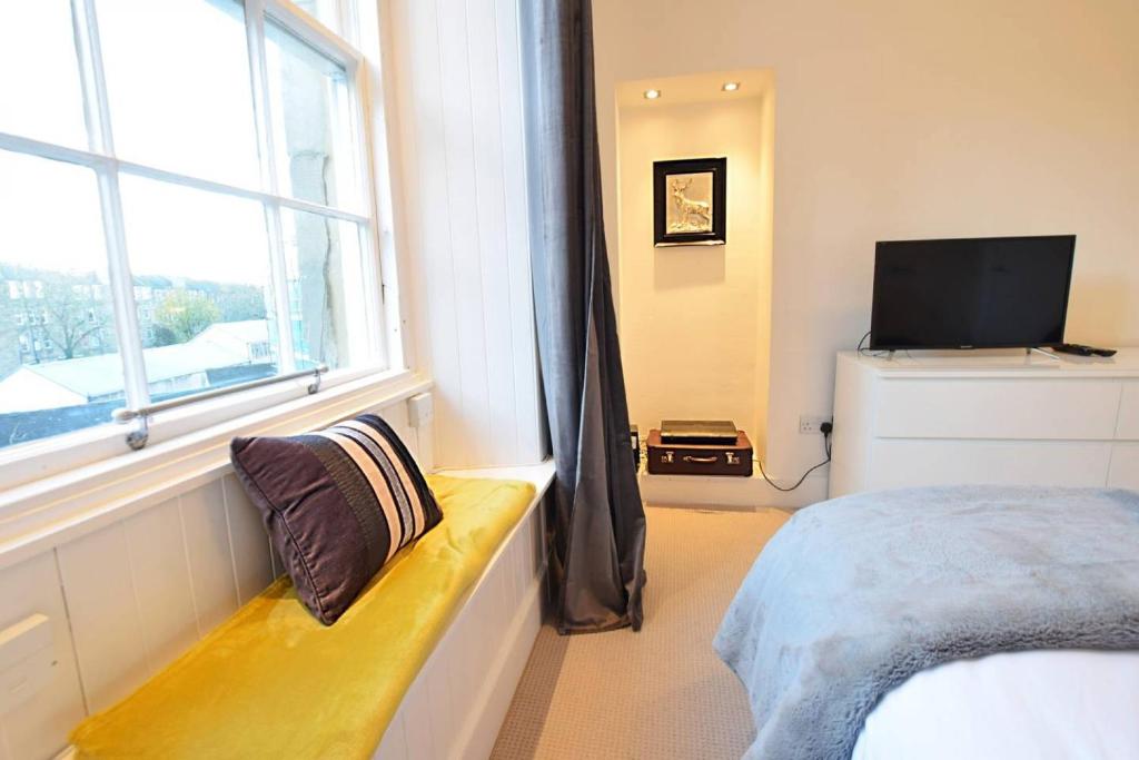 a bedroom with a window and a bed and a television at JOIVY Modern City Centre Flat next to Calton Hill in Edinburgh