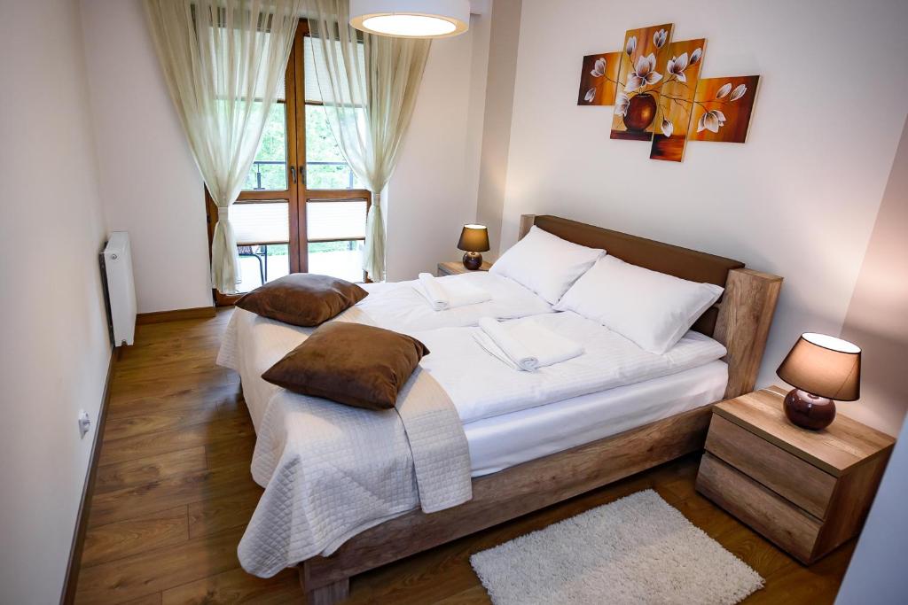 a bedroom with a large bed with white sheets and pillows at Apartamenty Sun & Snow Zielona in Krynica Zdrój