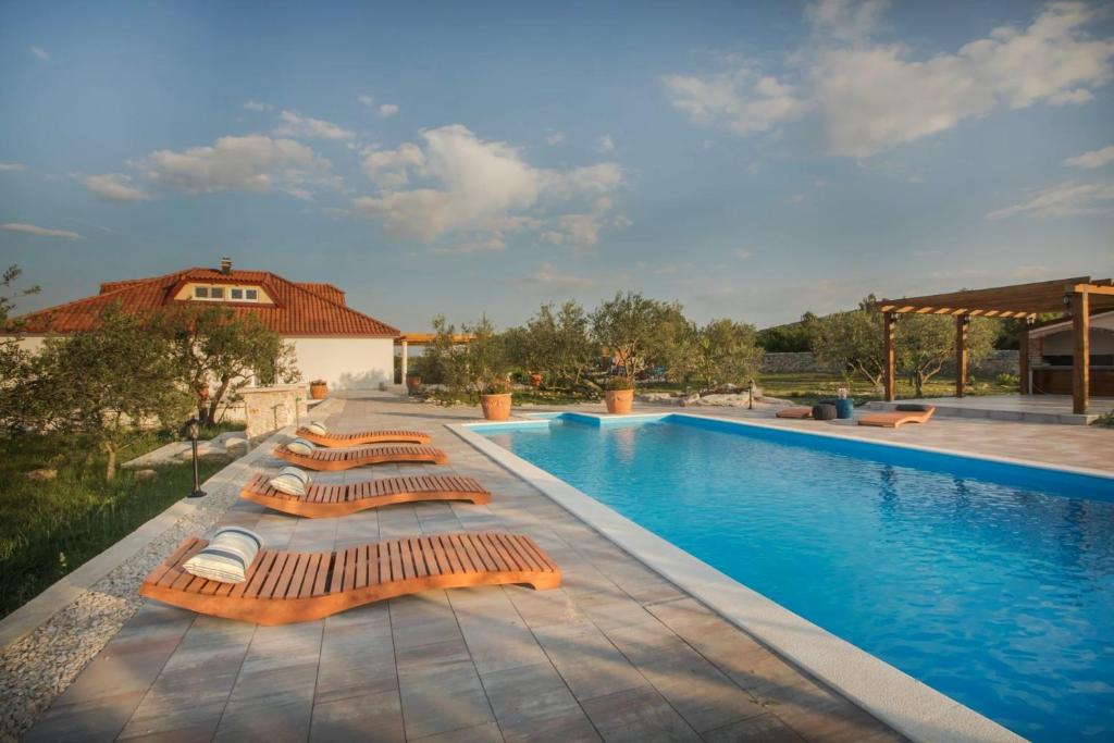 a row of lounge chairs next to a swimming pool at Villa Red Hacienda with Pool in Vodice