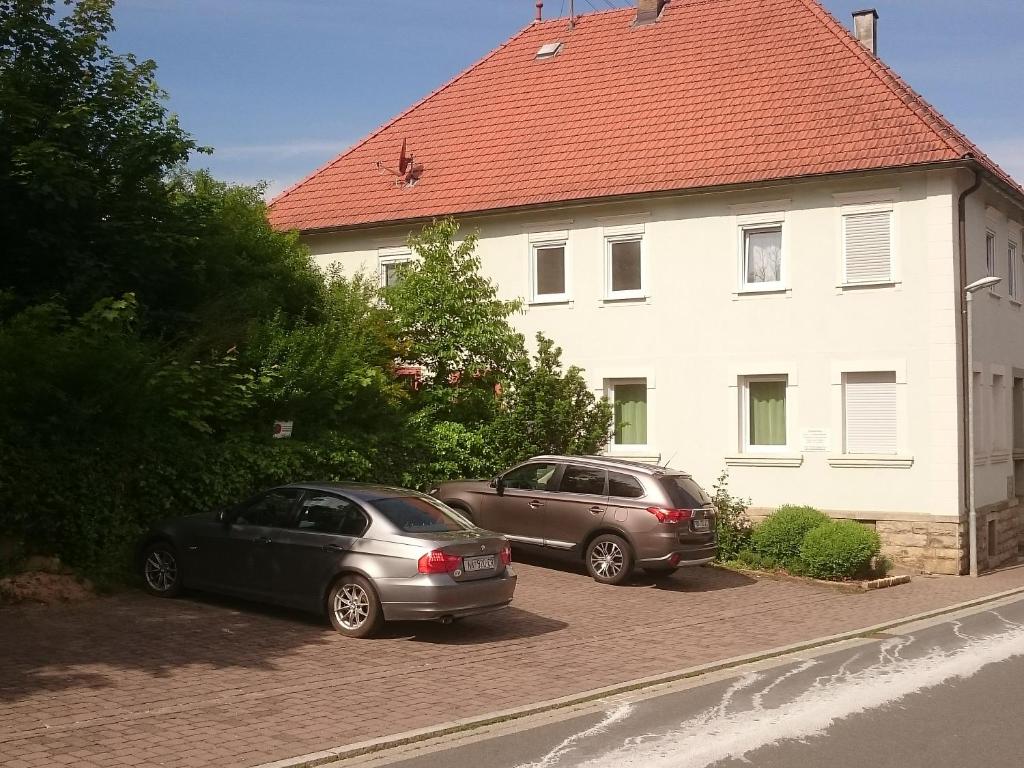 Deux voitures garées sur un parking en face d'une maison dans l'établissement Ferienwohnung Alte Linde, à Hardheim