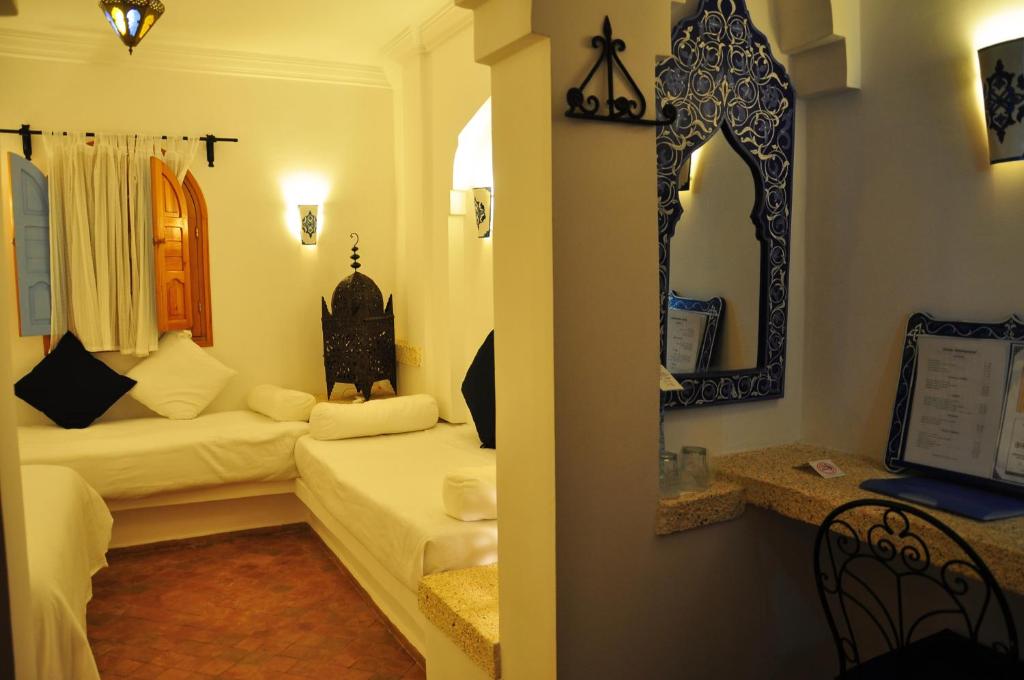 a living room with two beds and a mirror at Hotel Al Alba Hammam & Restaurant in Asilah