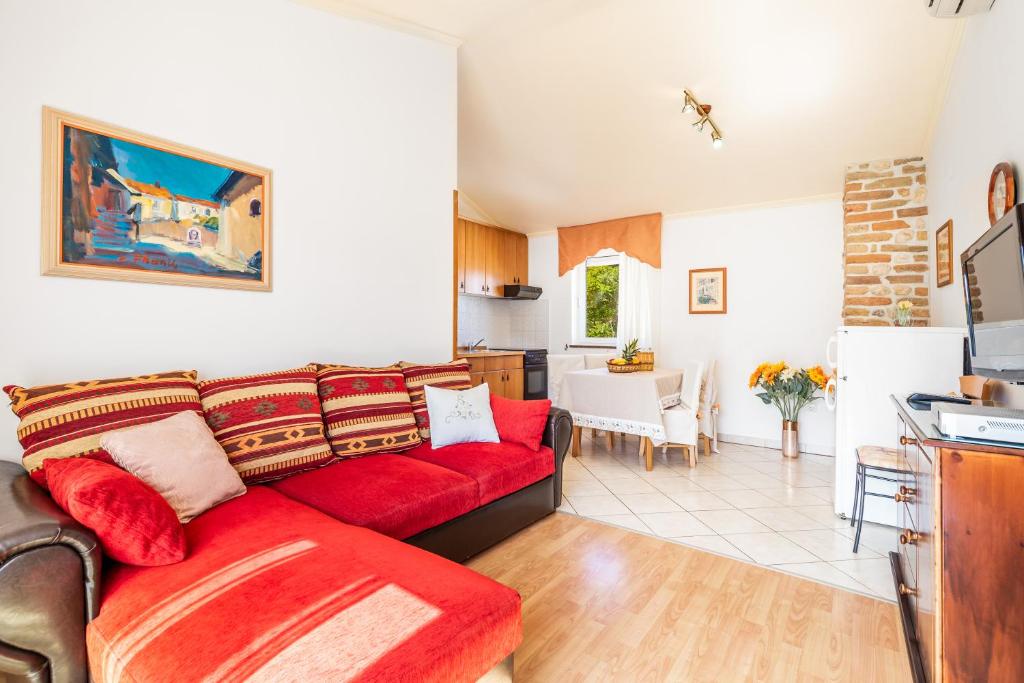 a living room with a red couch and a kitchen at Apartments Patricia in Baška
