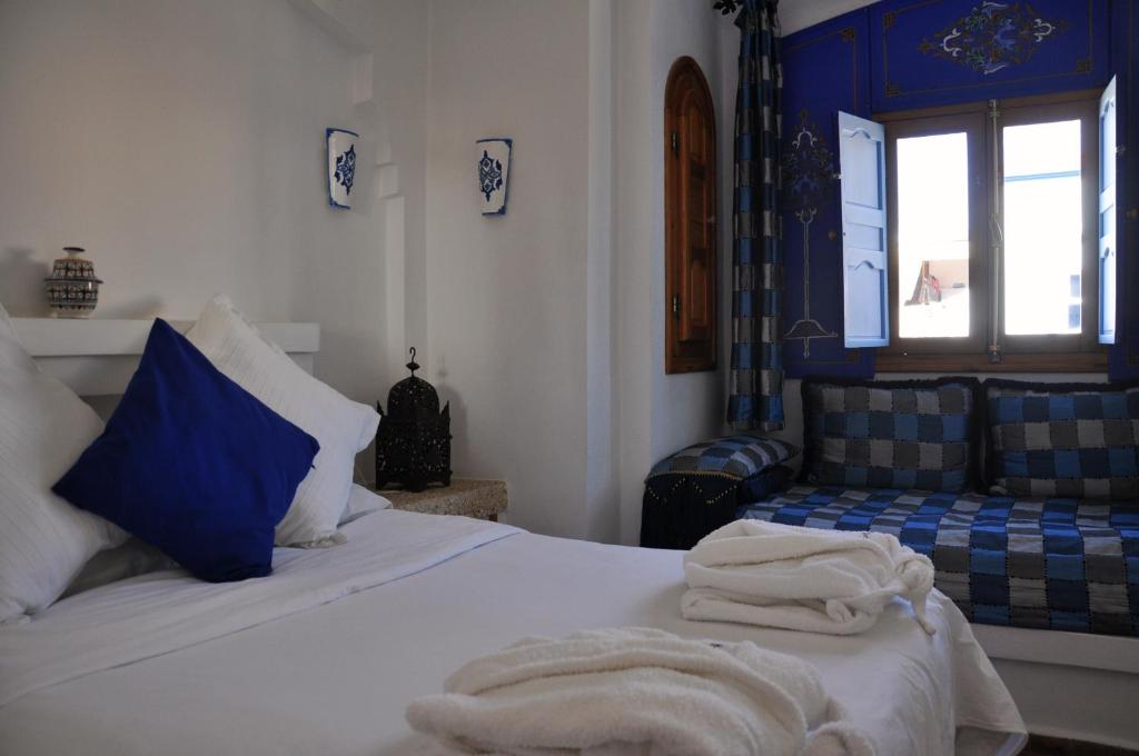 a bedroom with a bed with blue and white at Hotel Al Alba Hammam & Restaurant in Asilah