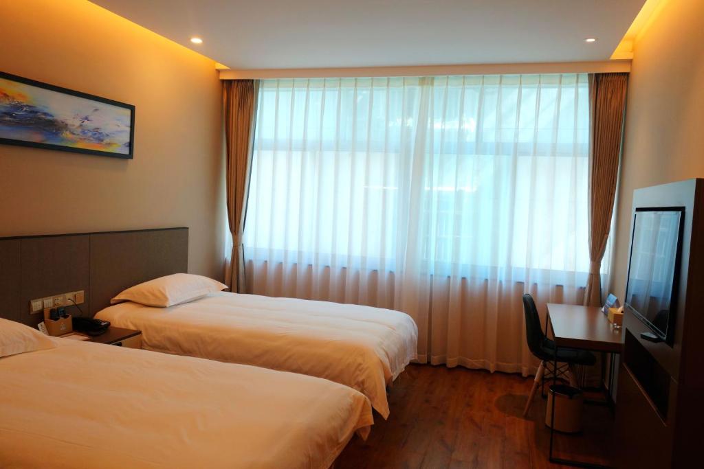 Hangzhou Yuqi Hotel في هانغتشو: غرفة فندقية بسريرين ونافذة