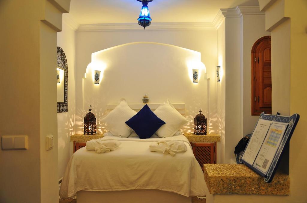 a bedroom with a large white bed with blue pillows at Hotel Al Alba Hammam & Restaurant in Asilah