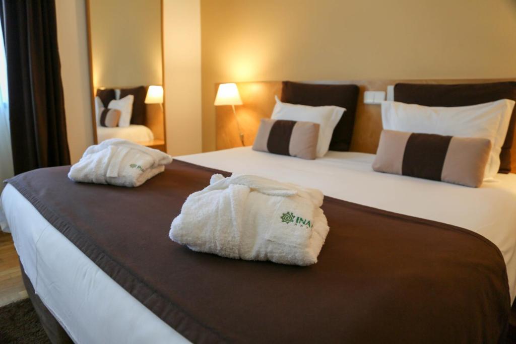 two towels on a bed in a hotel room at INATEL Caparica in Costa da Caparica