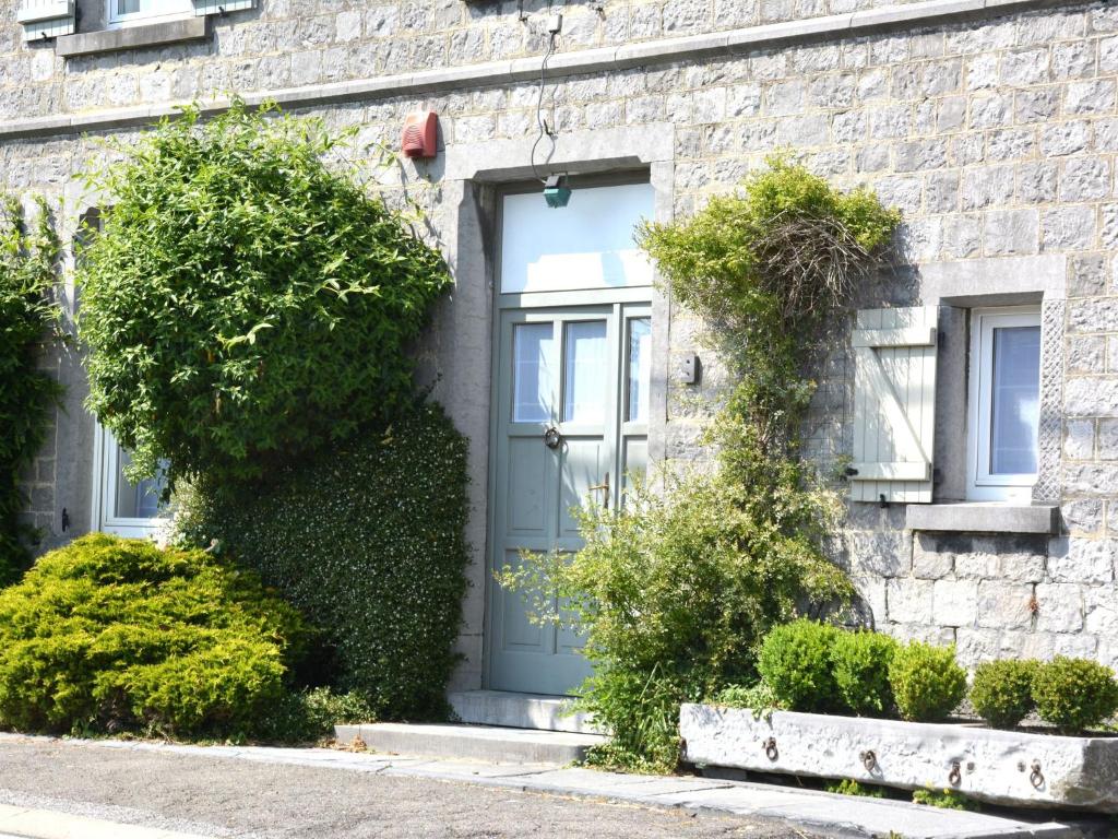 una casa de ladrillo con una puerta azul y arbustos en Spacious Holiday Home with Private Terrace, en Denée