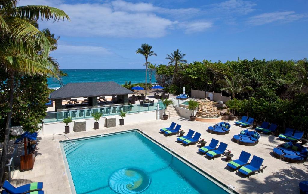 una vista aérea de una piscina con sillas y el océano en Jupiter Beach Resort & Spa, en Jupiter