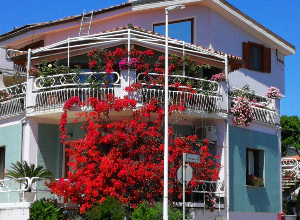 un edificio con fiori rossi sul lato di Il giardino all'angolo a Villacidro