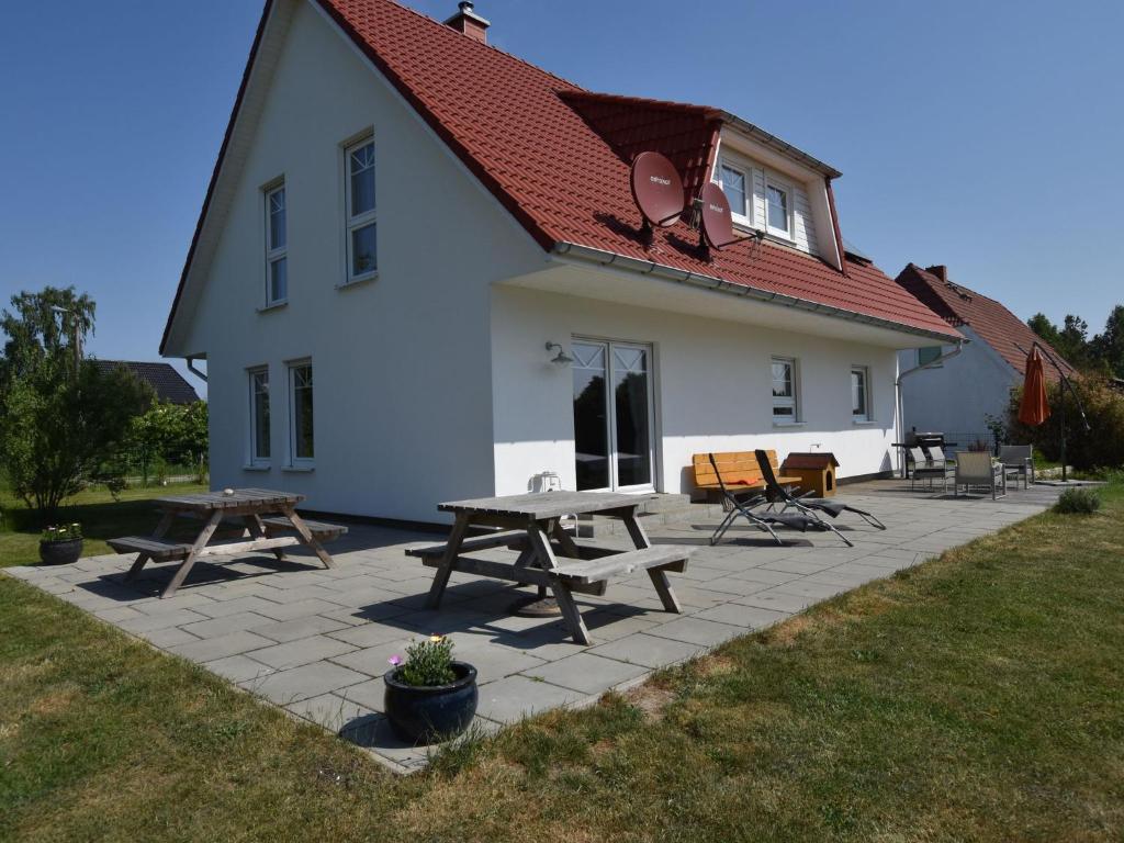 a white house with picnic tables in front of it at Spacious Holiday Home in Hornstorf with Trampoline in Hornstorf