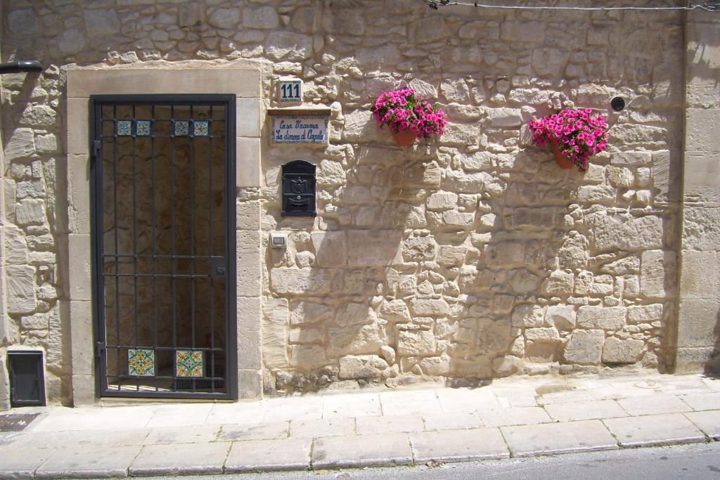 um edifício de pedra com uma porta e flores sobre ele em La Dimora di Angela em Ragusa