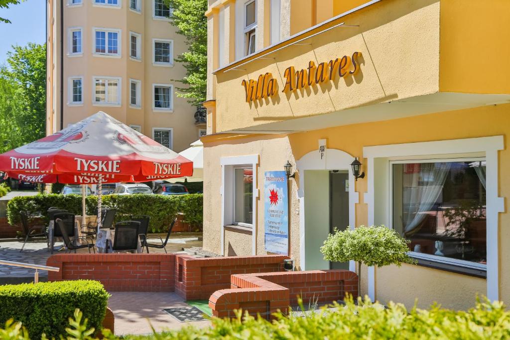 a building with a restaurant with a table and an umbrella at Villa Antares I & II in Świnoujście
