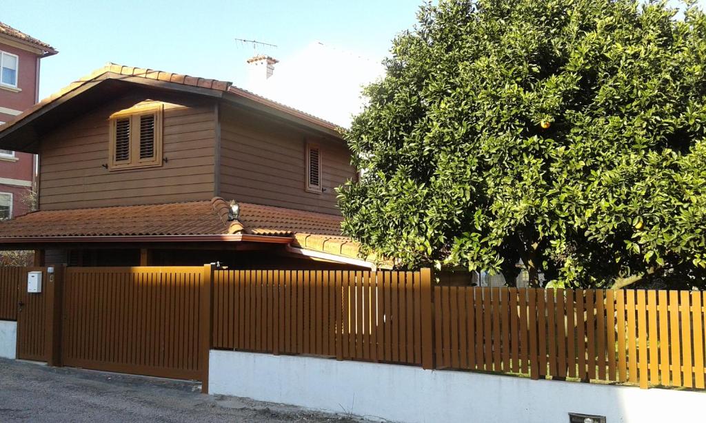 a brown house with a fence and a tree at Casa de Madera in Cangas de Morrazo
