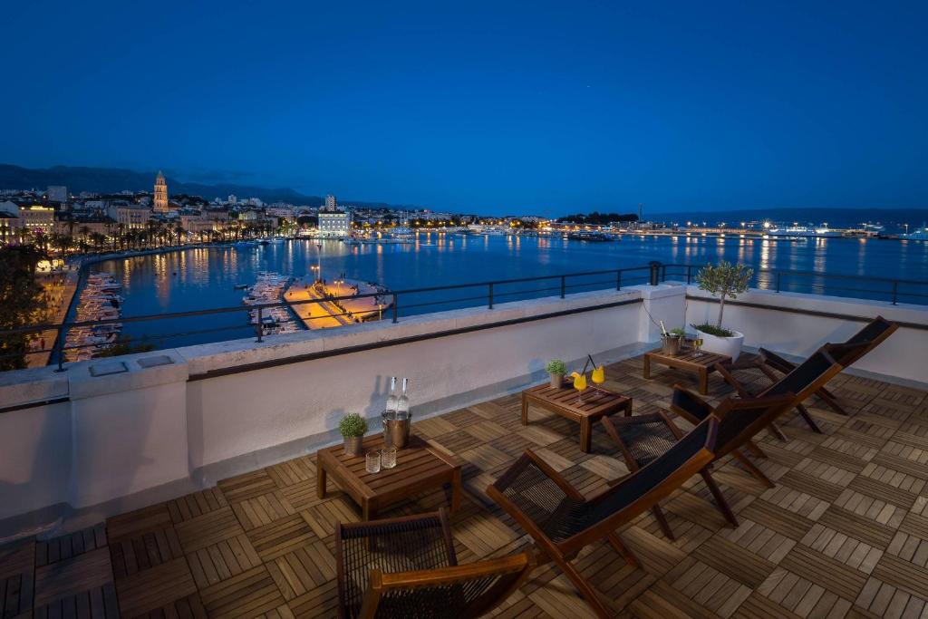 a balcony with tables and chairs and a view of the water at Belvedere Luxury Rooms - Breathtaking View in Split