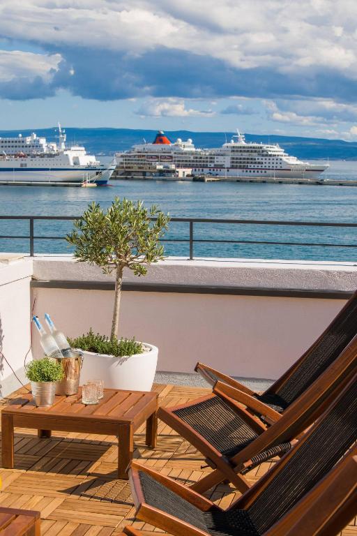 a balcony with two chairs and a table and some ships at Belvedere Luxury Rooms - Breathtaking View in Split