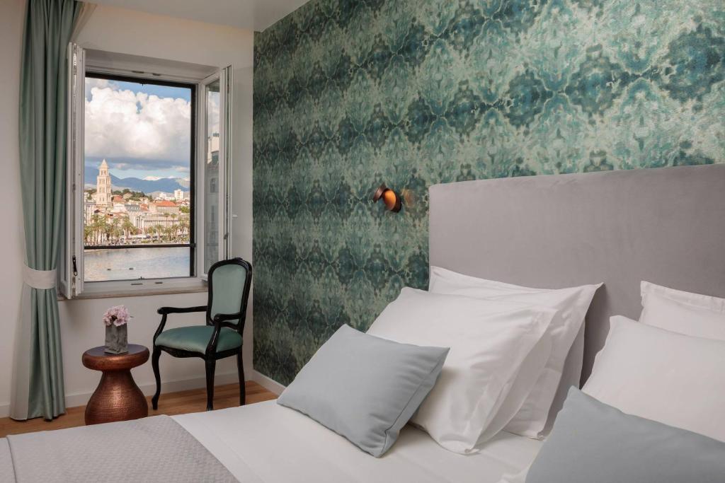 a bedroom with a bed and a window and a chair at Belvedere Luxury Rooms - Breathtaking View in Split