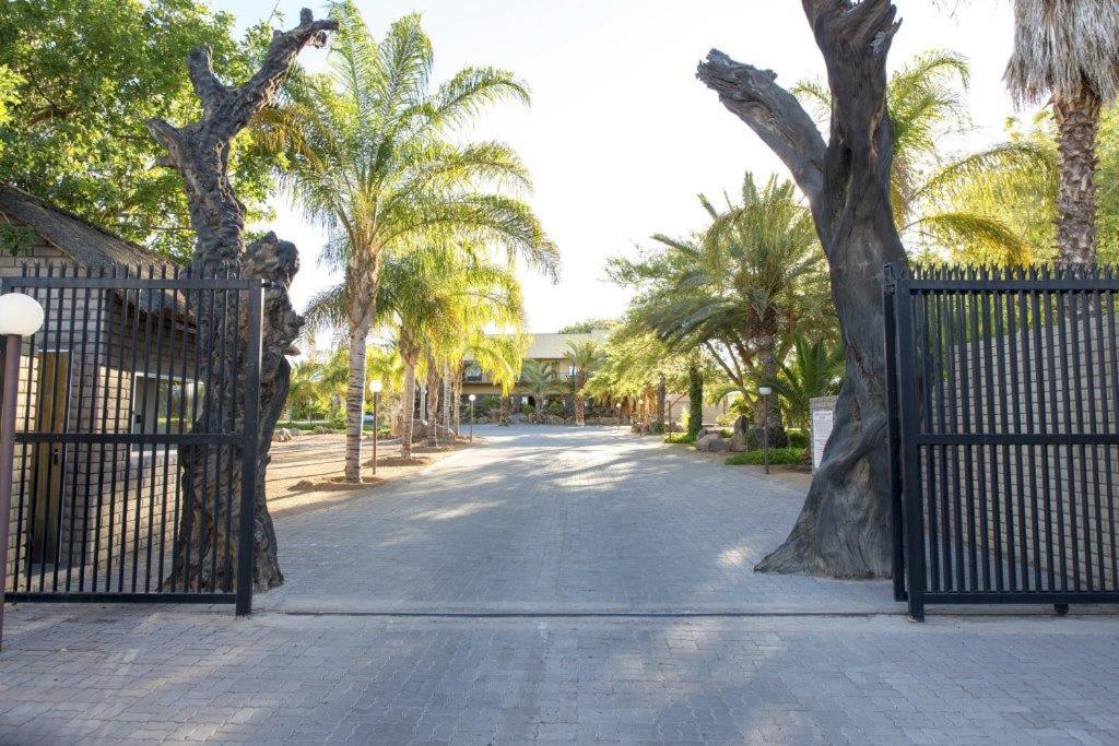 an open gate with palm trees on a street at Augrabies Falls Lodge & Camp in Augrabies