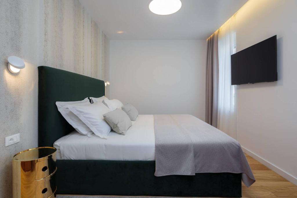 a bedroom with a bed with white sheets and pillows at Belvedere Luxury Rooms - Breathtaking View in Split