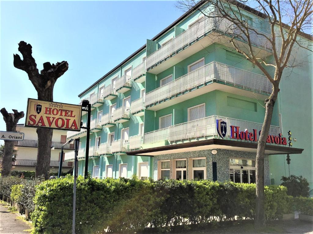 un edificio verde con un cartel delante en Hotel Savoia, en Lido di Jesolo