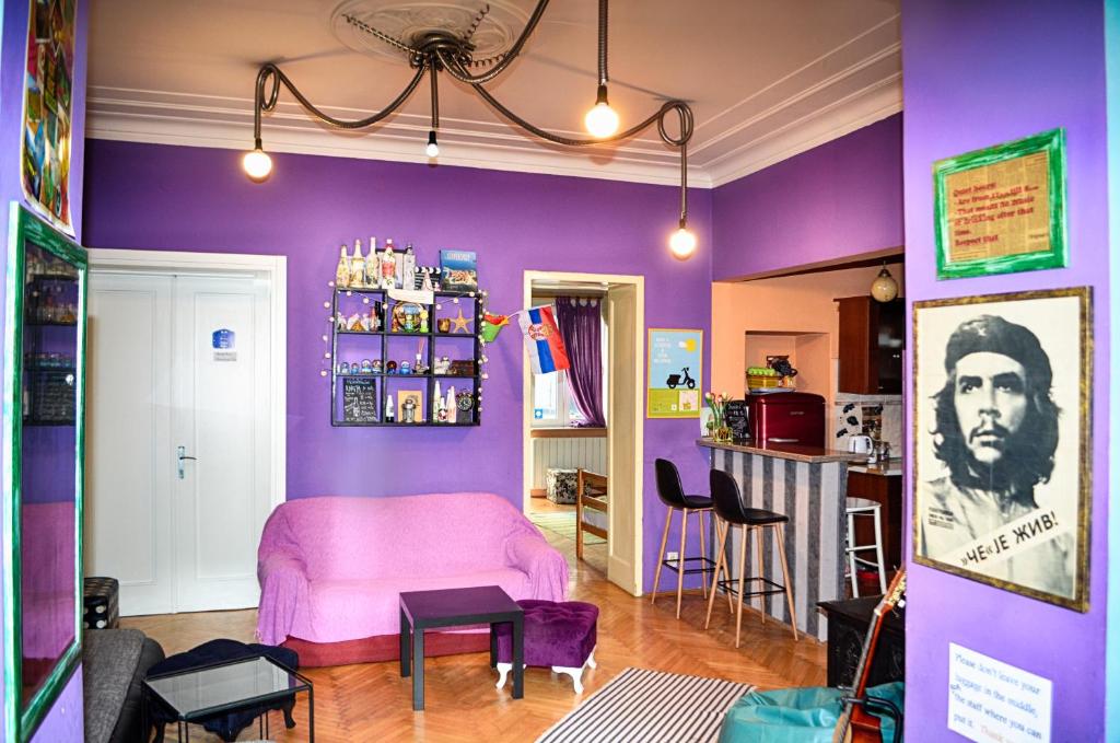 a living room with purple walls and a pink couch at HostelChe Hostel in Belgrade