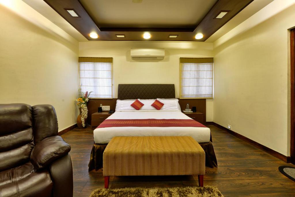 um quarto com uma cama, uma cadeira e um sofá em Pleasant Boulevard MG road em Bangalore