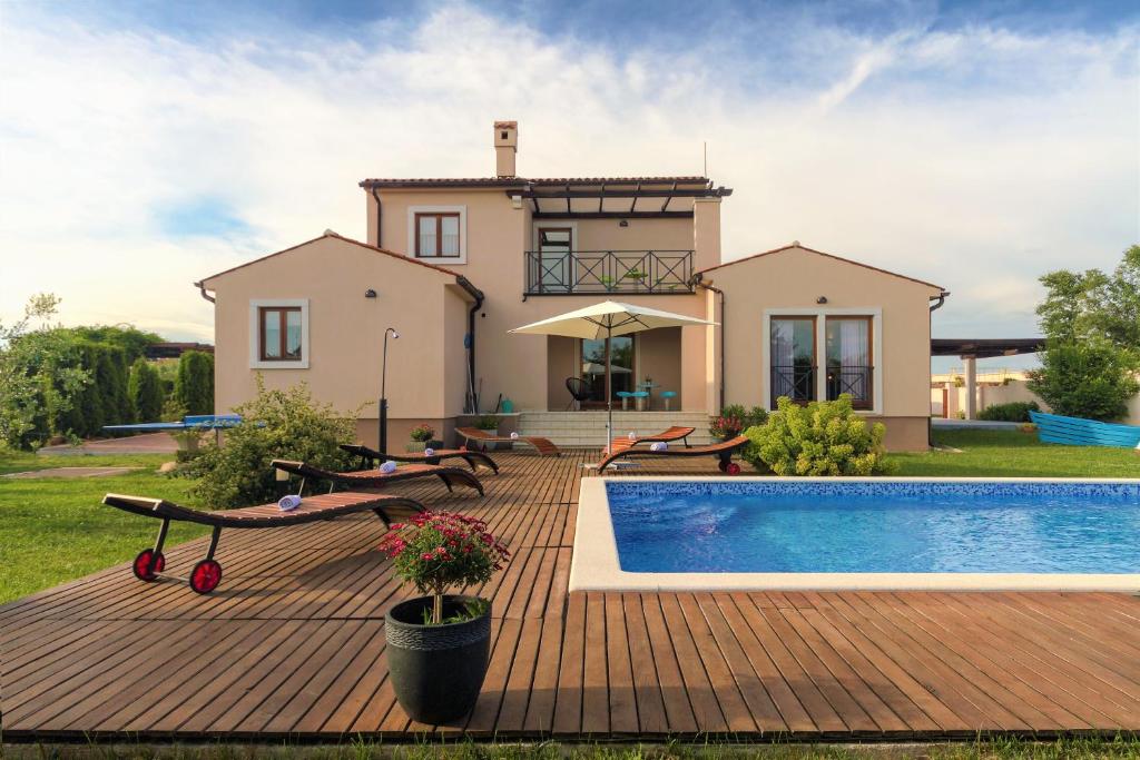 a villa with a swimming pool in front of a house at Villa NaNa - modern Villa with a pool surrounded by nature, Istria-Pula in Valtura