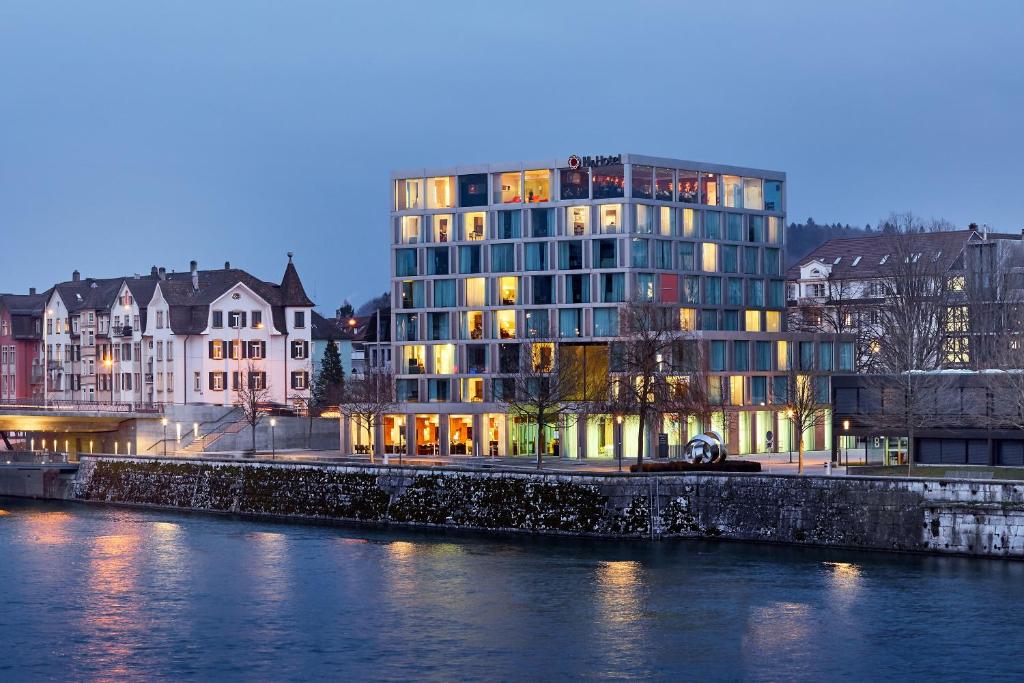 um edifício alto ao lado de um rio com edifícios em H4 Hotel Solothurn em Solothurn