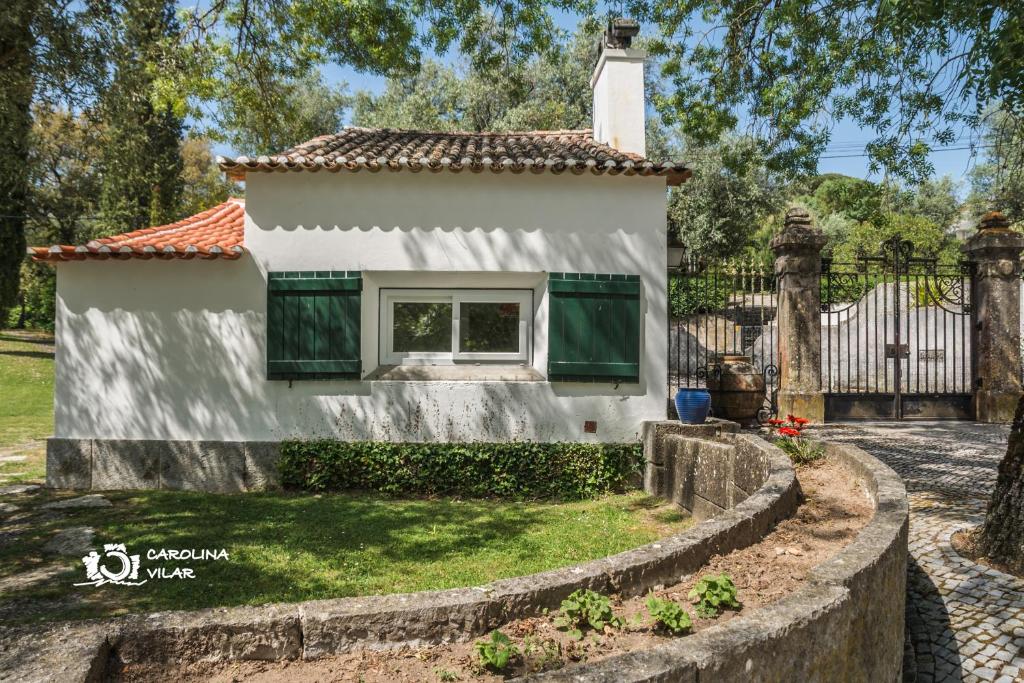 uma casa branca com janelas verdes e uma cerca em The Gate House em Bucelas