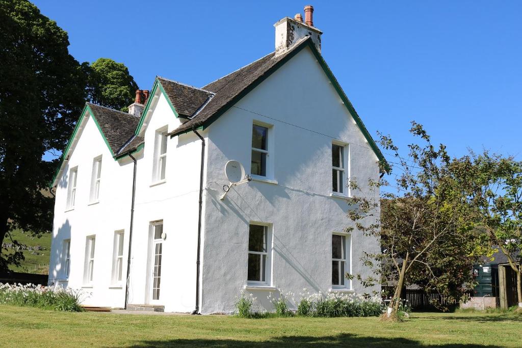 uma antiga casa branca com um telhado preto em Innishewan Farmhouse em Crianlarich
