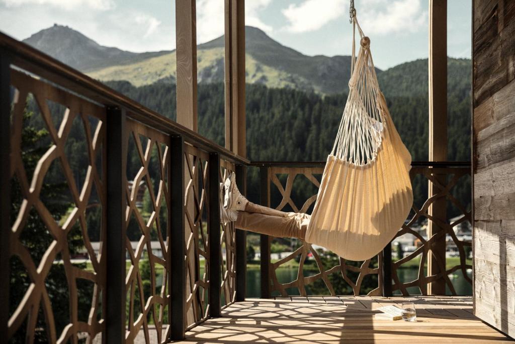 a hammock hanging on a porch with a view of mountains at Valsana Hotel Arosa in Arosa
