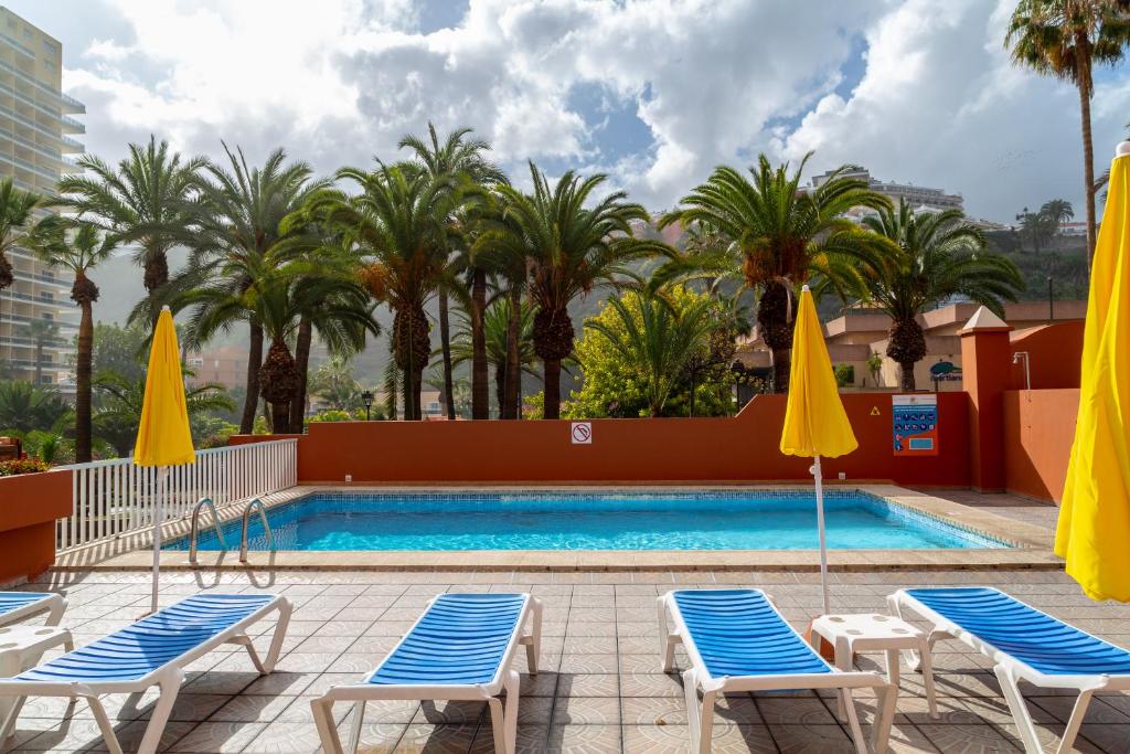 a swimming pool with two chairs and two umbrellas at Apartamentos Alta in Puerto de la Cruz