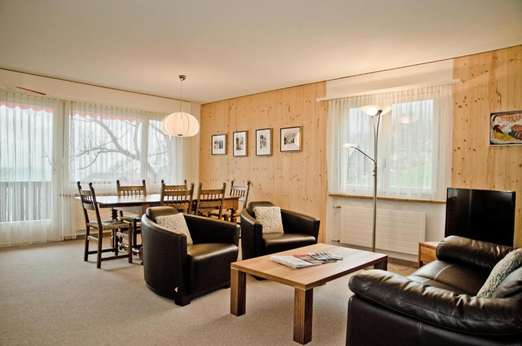 Apartment Schönegg - GRIWA RENT AG في جريندلفالد: غرفة معيشة مع طاولة وغرفة طعام
