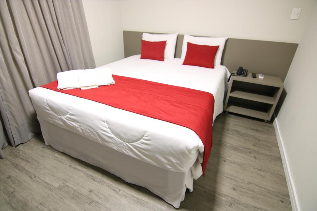 a bedroom with a large bed with red pillows at Lagoa Flat Hotel in Lagoa da Prata