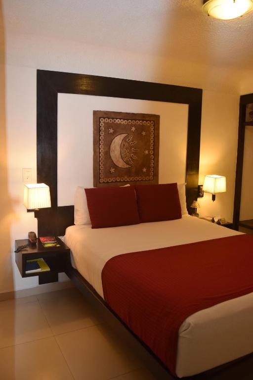 a bedroom with a large bed with red pillows at Choco's Hotel in Villahermosa