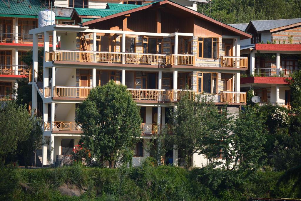 a large apartment building with balconies and trees at Himalaya Cottage in Manāli